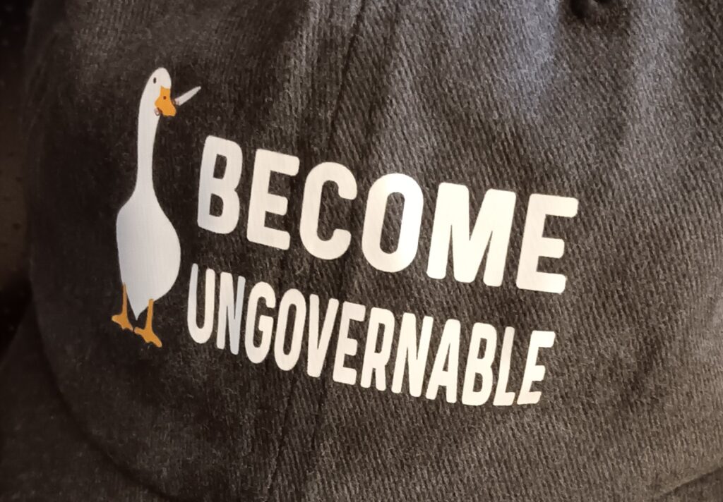 The front of a hat that reads "become ungovernable," with a goose holding a knife.